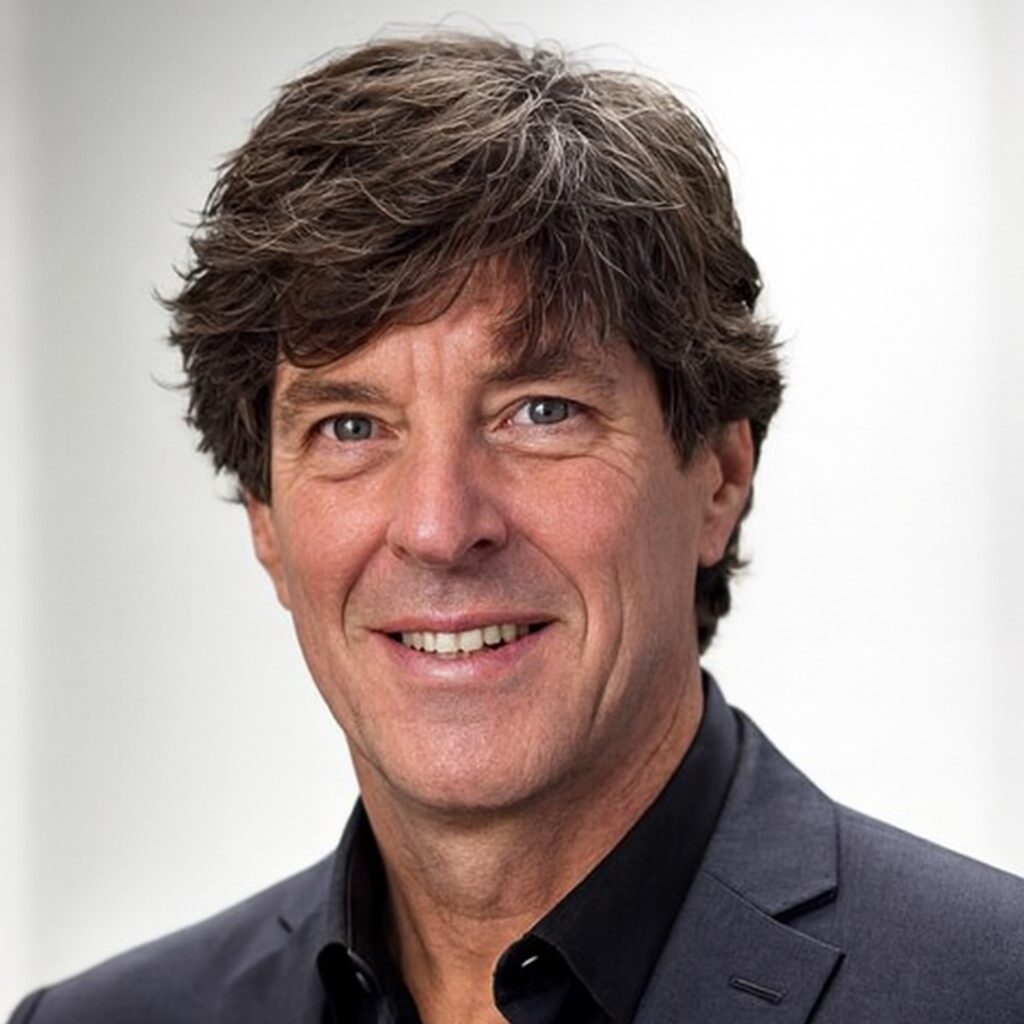 Porträt eines lächelnden Mannes in Anzug vor neutralem Hintergrund.