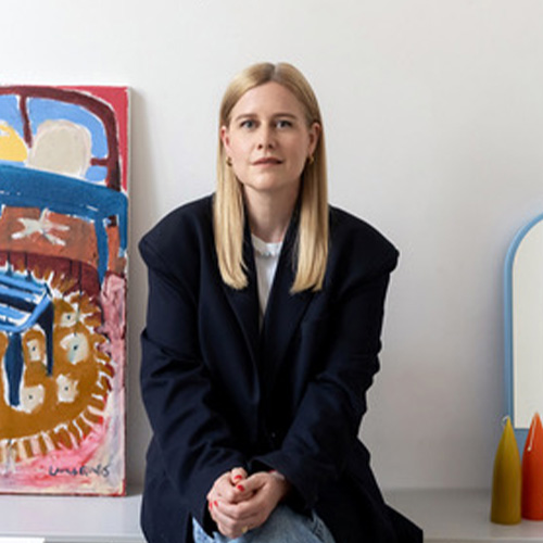 Person sitzt in modernem Raum mit abstrakter Kunst im Hintergrund.